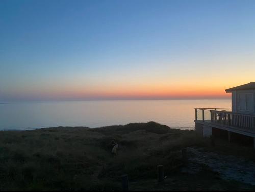 a person standing on a hill near a house with the ocean at Seaview Caravan, Perran Sands in Perranporth