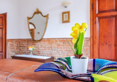 a vase with a yellow flower on a table at Hostly - Il Gelsomino di San Prospero in Cascina