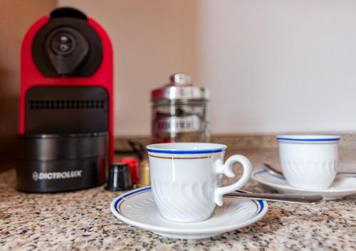 two coffee cups sitting on a counter next to a toaster at Hostly - Il Gelsomino di San Prospero in Cascina