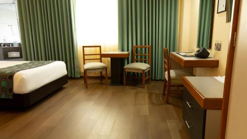 a hotel room with a bed and a desk and chairs at Hotel Abastos Plaza in Mexico City