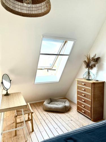 a attic room with a window and a dresser at Svencele mini cottage apartment in Svencelė