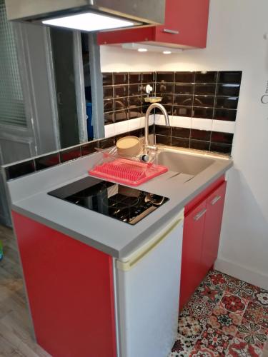 une cuisine avec des armoires rouges et un évier dans l'établissement idéal festival joli studio climatisé, à Avignon