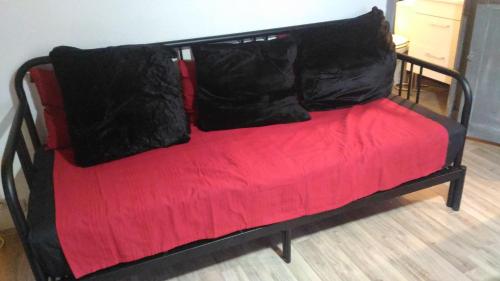 un canapé rouge avec des coussins noirs dessus dans l'établissement idéal festival joli studio climatisé, à Avignon