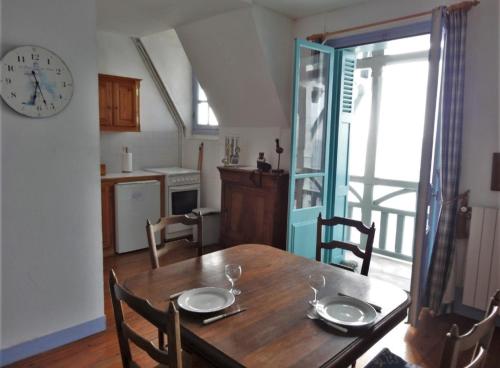 une salle à manger avec une table en bois et une horloge dans l'établissement le Tourbillon, à Mers-les-Bains