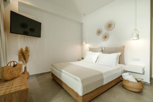 a white bedroom with a bed and a flat screen tv at Ninemia Luxury Residence in Perdika