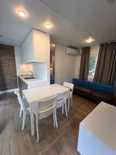 a kitchen and living room with a white table and chairs at Dune Prestige & Chalets in Bibione