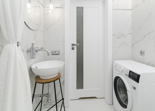 a bathroom with a sink and a washing machine at Apartamenty Mielenko Wichrowe Wzgórze in Mielno