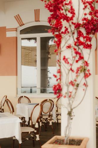 a vase filled with red flowers in a restaurant at HOTEL DEL GOLFO in Finale Ligure