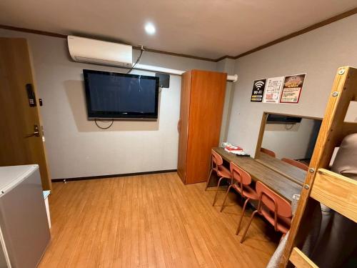 a room with a table and a television on the wall at Tokyo House INN in Tokyo