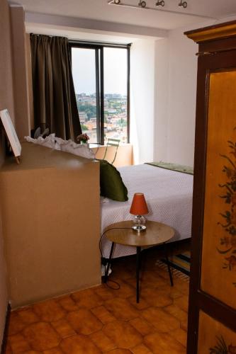 a bedroom with a bed and a table and a window at Jardim do Morro Places in Vila Nova de Gaia