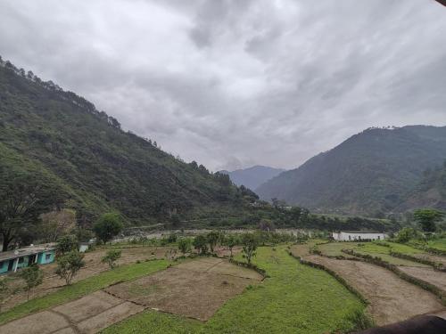 a view of a field with mountains in the background at Sri Shakti Hotel and restaurant in Chandrāpuri