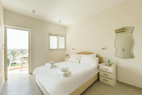 a white bedroom with a large bed and a window at Skyline 1BR Apartment with City and Sea View Sea N' Rent in Herzliyya B