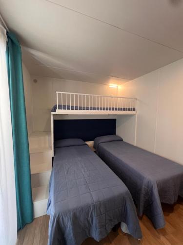 two beds in a small room with a bedvisor at Dune Prestige & Chalets in Bibione
