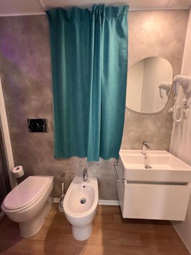 a bathroom with a toilet and a sink and a mirror at Dune Prestige & Chalets in Bibione
