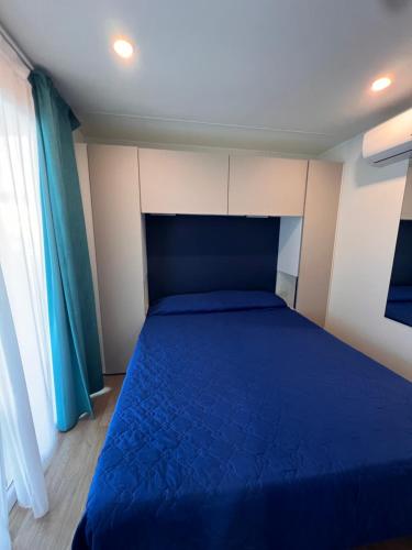 a bedroom with a blue bed in a room at Dune Prestige & Chalets in Bibione