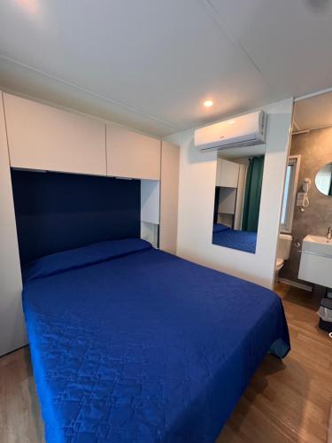 a bedroom with a blue bed and a sink at Dune Prestige & Chalets in Bibione