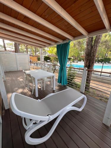 a white bench on a deck with a table at Dune Prestige & Chalets in Bibione
