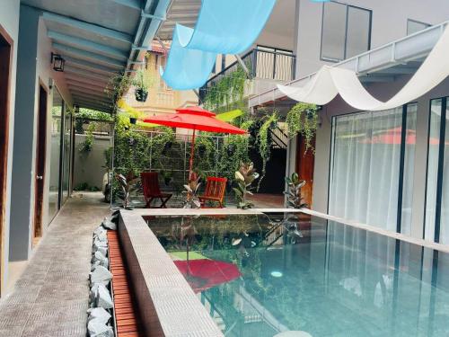 a swimming pool with a red umbrella and chairs at 5Mins from central Siem Reap and Pool at your door in Phumĭ Réach Born