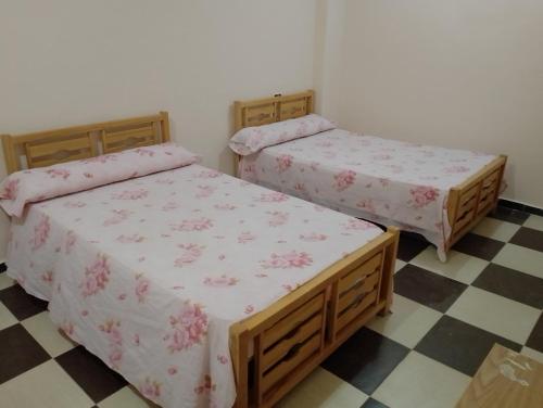 two twin beds in a room with a checkered floor at برج القط للشقق الفندقيه المفروشة in Marsa Matruh