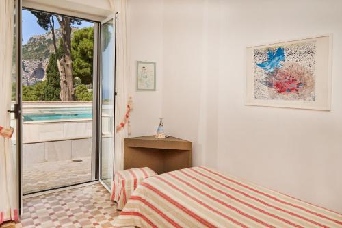 a bedroom with a bed and a view of a pool at Villa dei Galli - via Tragara in Capri
