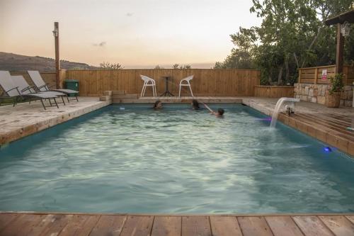 a swimming pool with a deck and chairs in it at גרין פארק - קוטג' מהמם עם בריכה וג'קוזי בעין קנייא in Ein Kinya