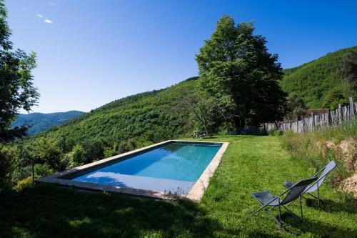 une piscine et une chaise dans l'herbe dans l'établissement Grand mas catalan en pleine nature avec piscine, à Céret