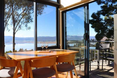 a dining room with a table and chairs and large windows at The Tamar Ridge Lookout at Tamar Ridge Apartments in Grindelwald