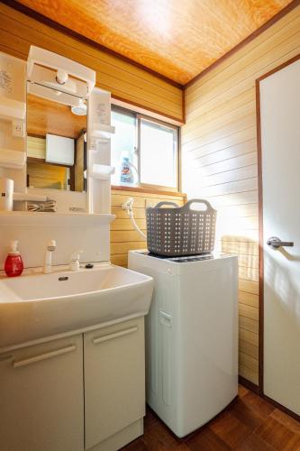 a small bathroom with a sink and a white refrigerator at Mizunara Terrace Karuizawa in Karuizawa