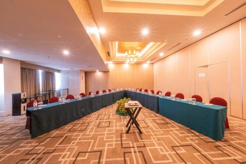 a conference room with a long table and red chairs at Grand Jatra Hotel Balikpapan in Balikpapan