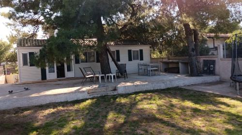 a house with a table and chairs in a yard at Family mobile home solar powered near the sea and the airport in Áyios Spirídhon