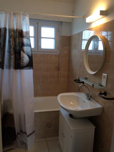 une salle de bain avec un lavabo, une baignoire et un miroir dans l'établissement Maison familiale avec piscine, à Barbâtre