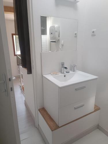 une salle de bain blanche avec un lavabo et un miroir dans l'établissement Maisonnette dans hameau provençal, à Cabriès