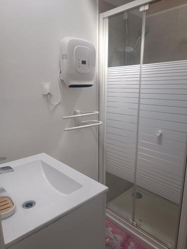 une salle de bain blanche avec une douche et un lavabo dans l'établissement Maisonnette dans hameau provençal, à Cabriès