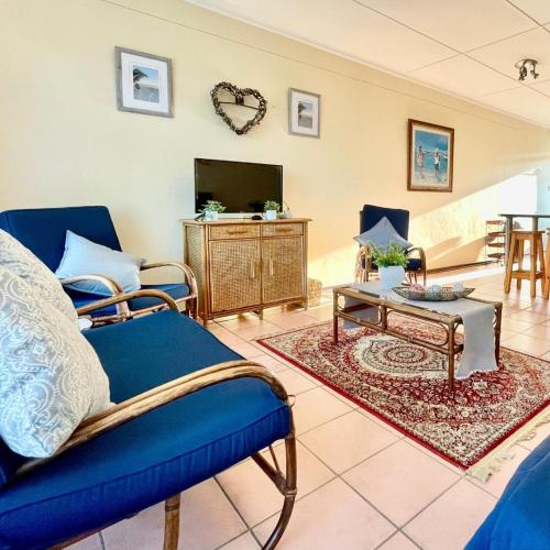 a living room with a blue couch and a tv at Jakaranda 22 apartment, Uvongo in Uvongo Beach