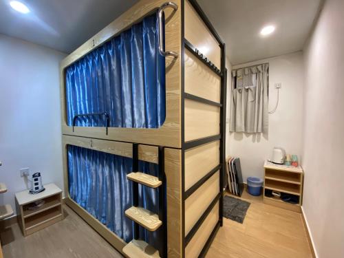 a room with a bunk bed with blue curtains at Timehouse Hong Kong Hostel Group in Hong Kong