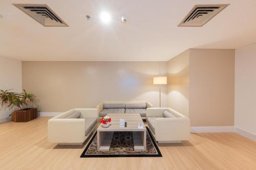 a living room with a couch and a table at Grand Jatra Hotel Balikpapan in Balikpapan