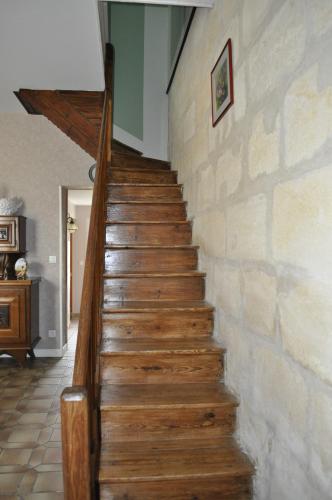 a wooden staircase in a house with a stone wall at Chambres d'Hotes La Mouline in Ludon-Médoc