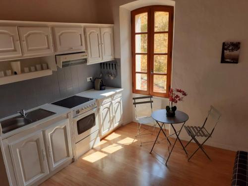 a kitchen with white cabinets and a table and a window at French Cocoon in Fayence