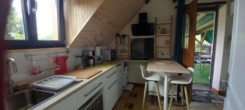 une cuisine avec un évier et un comptoir avec des tabourets dans l'établissement Gîte de la Poterie Fenêtre sur Loire, à Mosnes