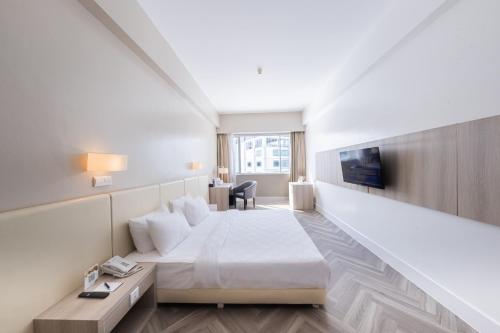 a hotel room with a bed and a desk at Grand Jatra Hotel Balikpapan in Balikpapan