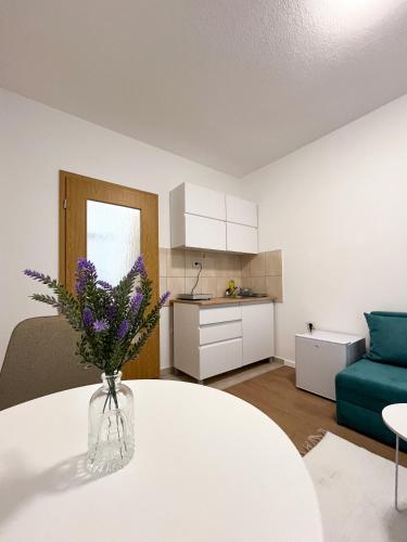 a living room with a table with purple flowers in a vase at Modern Central Studio - 3 min walk to lake in Ohrid