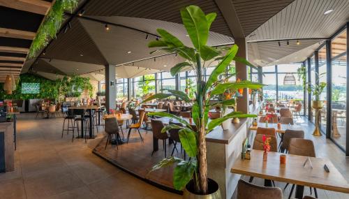 a restaurant with tables and chairs and a plant at Vakantiepark Leukermeer in Well
