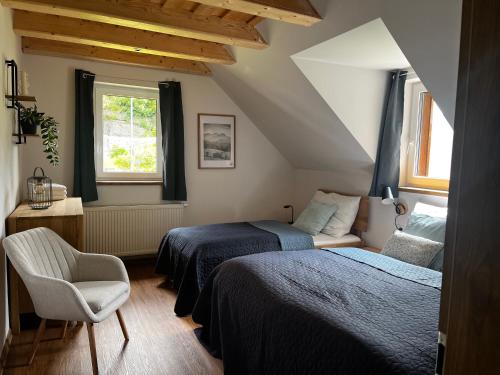 a bedroom with two beds and a chair and a window at U Křížku - Chalupa s duší in Desná