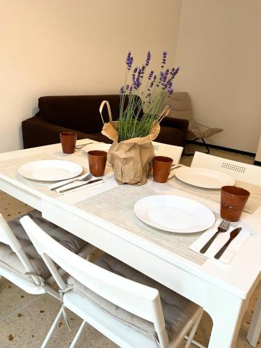 a white table with plates and purple flowers on it at Cà di Scirocco in Varigotti