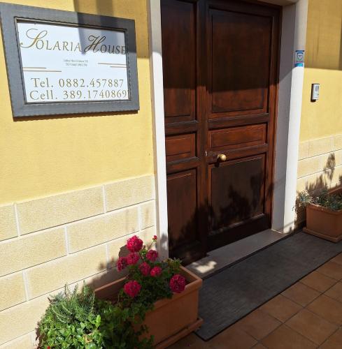 a sign on the door of a house with flowers at Solaria House appartamenti con cucina a 200 MT dalla Basilica di Padre Pio e 600 MT dall'ospedale Casa Sollievo della Sofferenza in San Giovanni Rotondo