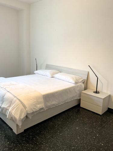 a bed with white sheets and a lamp on a night stand at Cà di Scirocco in Varigotti