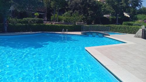 a large blue swimming pool with a bench in it at Apartments Nicole in Porto Rotondo