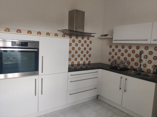 a kitchen with white cabinets and silver appliances at VILLA PROCHE de la PLAGE, VUE MER avec PARKING in LʼÎle-Rousse