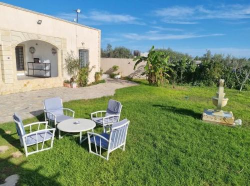 a patio with chairs and a table in the grass at Dar Nawara 3bedroom Villa with pool and amazing garden in Tazarka