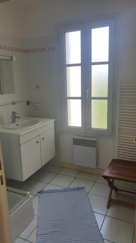 une salle de bain blanche avec un lavabo et une fenêtre dans l'établissement Jolie maison au calme jardin plage a proximité, à Meschers-sur-Gironde